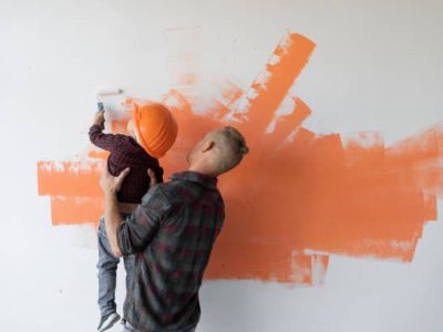 repairs his house, the father keeps his son and he helps him paint the wall with a roller, copy space